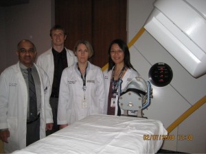 Two female and two males standing in front of medical imaging device.