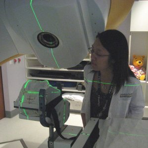Female standing over medical imaging device.