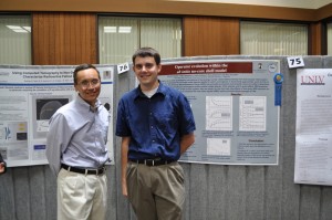 Two males standing in front of posters.